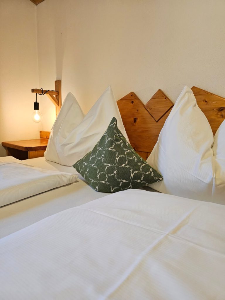 Gemütliches Bett mit Kissen und Holzdetails in einer Ferienwohnung in Flachau.