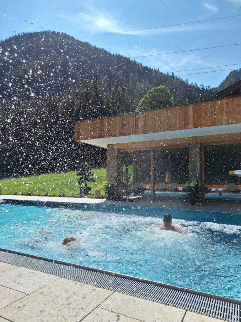 Wasserspritzer im beheizten Außenpool des Hinterrohrguts in Flachau, Österreich – ideal für Familien aus Deutschland, den Niederlanden, Belgien und Österreich.