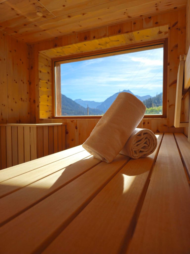 Saunabereich mit Holzregalen und Handtüchern, Blick auf die Berge in Flachau.
